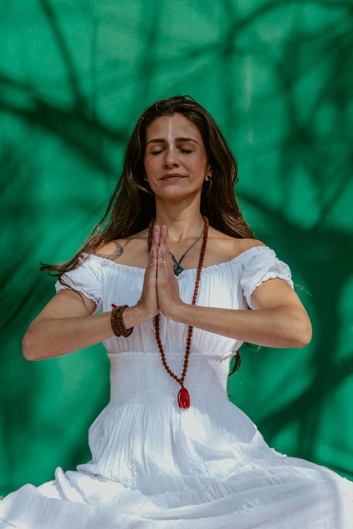 services-03 Calm and relaxed woman meditating outdoors with a vibrant green background.